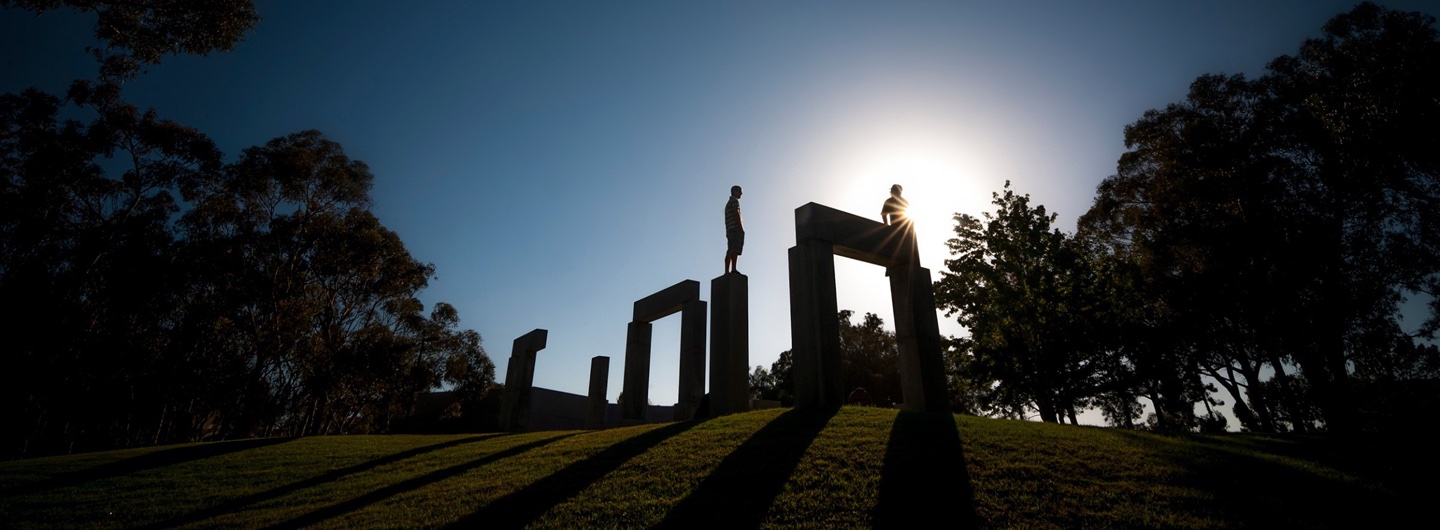 students standing atop stonehenge rocks on lawn